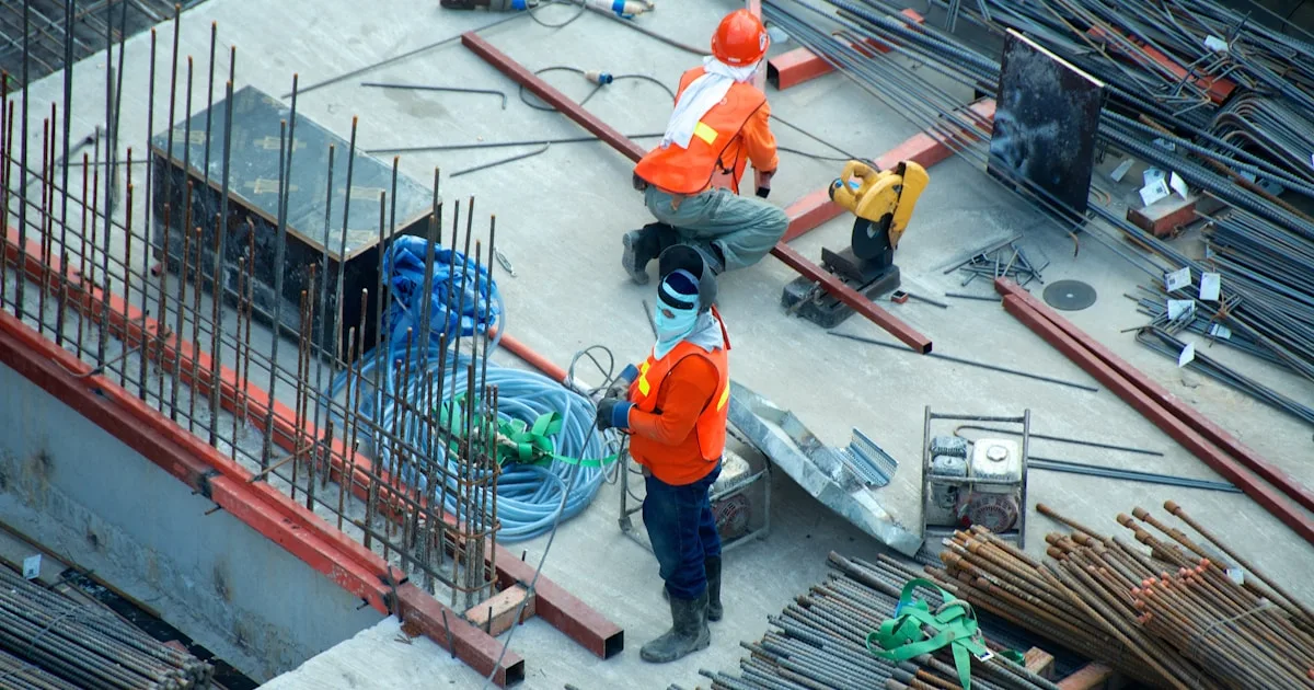 Two construction workers wearing hard hats and high-visibility clothing on a building site