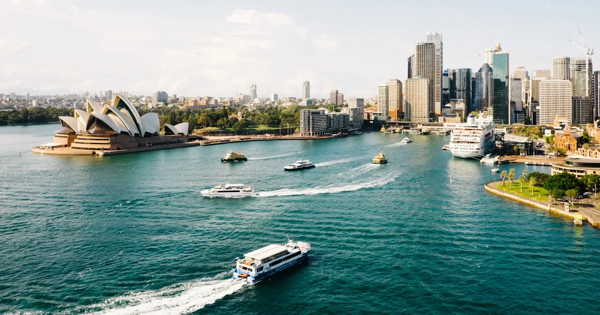 Split view of Sydney Harbour Bridge and Melbourne city skyline comparing cost of living